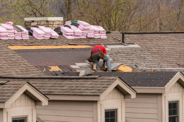 Roofing contractor removing the old shingles from a roof ready for reroofing